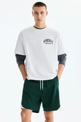 Short deportivo de color verde oscuro, confeccionado en nylon, con bandas laterales blancas, cintura elástica ajustable mediante cordón blanco y corte estándar.