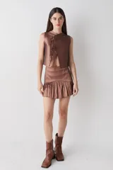 Top sin mangas de estilo cruzado, confeccionado en tela satinada color cobre. Presenta un diseño corto con cierre frontal mediante tiras finas para anudar y cuello redondo.