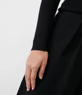 Blusa negra de punto con escote en U, mangas largas y detalle de tres botones dorados.