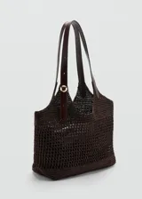 Bolso tipo tote color marrón con diseño de tejido calado de fibra natural, doble asa larga de hombro con detalle de hebilla ajustable y aplique metálico dorado, e incluye un bolso interno de tela con cierre de cremallera.