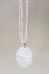 Collar de tres hileras de perlas pequeñas con un medallón central de nácar circular.