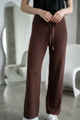 Pantalón de lanilla color marrón chocolate, de corte recto y tiro alto. Presenta una cintura elástica con cordón ajustable del mismo tejido y una textura acanalada vertical.