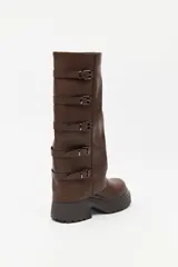 Bota de caña alta estilo biker, color negro, con plataforma robusta y suela dentada. Presenta múltiples tiras laterales con hebillas metálicas ajustables.