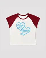 Baby tee de corte ajustado con mangas raglán en contraste color bordó. Presenta un estampado frontal de dos corazones en color celeste con la inscripción 'Made in Uruguay'.