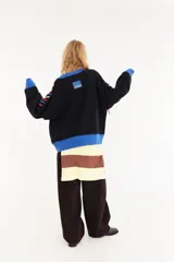 Sweater oversize de corte boxy, color crema con rayas verticales en tonos marrones y detalles de flecos colgantes. Presenta cuello redondo y puños y ruedo en tejido acanalado de color marrón oscuro.