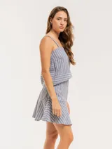 Falda corta color beige con rayas verticales blancas, corte evasé y volado en el ruedo.