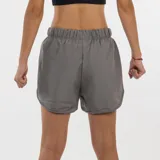 Short deportivo para mujer, color gris oscuro, con cintura elástica fruncida y aberturas laterales redondeadas en el ruedo. Presenta el logo de Diadora en material reflectante en la pierna derecha.