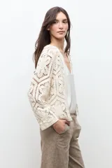 Chaqueta tejida a crochet en color beige claro, de diseño abierto y manga larga con patrones geométricos calados.