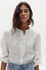 Camisa de lino blanca con bordados de pequeños corazones celestes, mangas abullonadas y cuello mao con volados en la botonera frontal oculta.
