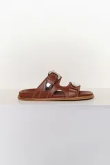 Sandalias marrones de cuero con dos tiras anchas sobre el empeine, hebillas plateadas y pespuntes en contraste.