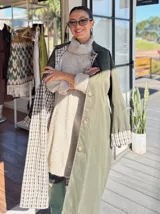 Trench reversible de corte clásico con cinturón ajustable. Un lado presenta un diseño liso en color verde militar, mientras que el reverso cuenta con un estampado a cuadros en tonos neutros. Posee cierre frontal con botones y cuello camisero.