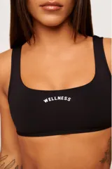 Top deportivo negro con breteles anchos y escote cuadrado. Estampado frontal con la palabra "Wellness" en color blanco.