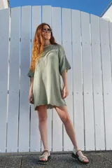 Vestido corto tejido de punto en color verde, con cuello redondo, mangas cortas holgadas y terminación con borde festoneado.