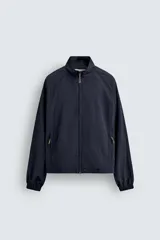 Chaqueta de corte relajado, color azul marino oscuro, confeccionada en tejido técnico ligero. Presenta cuello subido, forro interior de malla, bolsillos de vivo en cadera y bajo ajustable con elástico lateral. Cierre frontal con cremallera de doble dirección.