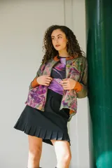 Chaqueta bomber con estampado abstracto en tonos verdes, rosas y naranjas. Tiene cuello, puños y ruedo acanalados en color naranja.