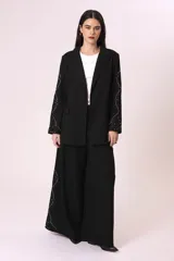 Pantalón palazzo negro con bordado de pequeñas tachas plateadas en forma de rombos a lo largo de la pierna.