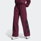 Pantalón deportivo Adidas Originals holgado de color bordó, con cintura elástica, tiro medio y detalles de tres tiras grandes negras en los laterales de las pantorrillas.