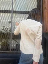 Cárdigan de lana color crudo, de tejido fino, con cuello redondo y cierre frontal de botones.