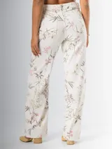 Pantalón wide leg de denim rígido con estampado floral chintz en tonos amarillo y rosa pastel sobre base blanca.