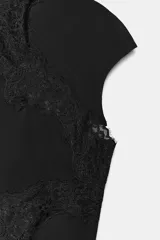 Top negro confeccionado en tejido elástico, con cuello perkins y mangas muy corta. Presenta un detalle de aplique de encaje a tono que cruza desde el cuello hasta el lateral de la prenda.