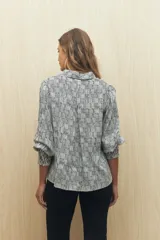 Camisa blanca con estampado lineal irregular en negro, de calce relajado, cuello clásico, abotonadura frontal y mangas largas con puños elastizados.