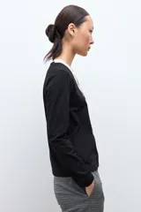 Remera de manga larga con diseño bicolor, presenta un panel central en color beige y laterales en color negro, con escote en V.