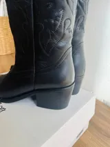 Botas texanas negras de cuero con bordados decorativos y taco bajo.