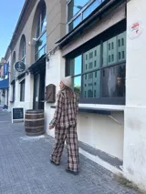 Pantalón de corte recto con estampado de cuadros en tonos marrones y blancos, con cintura elástica y cordón de ajuste.