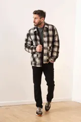 Campera de estilo camisa confeccionada en tela de lana a cuadros en tonos gris, negro y blanco. Presenta cierre frontal con botones, cuello clásico y bolsillos frontales.