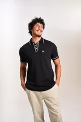 Polo de manga corta confeccionado en tejido interlock suave, color negro con detalles de vivos en color blanco en el cuello y las mangas. Presenta tapeta con botones y un bolsillo frontal con el logo bordado.