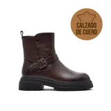 Bota de caña media confeccionada en cuero color marrón oscuro, con suela track de goma negra, detalle de tira con hebilla metálica en el tobillo y cierre lateral.