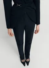 Pantalon de vestir negro de corte recto y tiro medio, con pliegues decorativos, trabillas para cinturón y cierre oculto. Incluye forro interior.