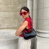 Cartera de hombro color marrón oscuro con textura de cocodrilo (efecto croco) y acabado brillante. Tiene forma de media luna y asa corta.