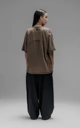 Remera de manga corta con calce oversize, confeccionada en algodón con proceso batik artesanal. Presenta recortes superpuestos y costuras expuestas en el frente, espalda y mangas.