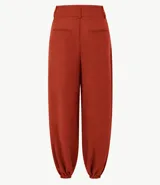 Pantalón balloon de piqué color terracota, con cintura estructurada, pinzas delanteras, pasacintos, piernas amplias y dobladillos elásticos.