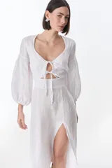 Vestido midi fucsia de lino, con escote en V, mangas largas abullonadas, lazos frontales y tajo lateral.