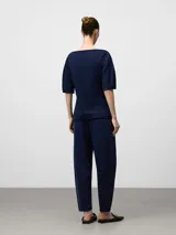 Pantalón jogger de punto color azul marino, de corte relajado y tiro alto, con pliegues frontales y puños ajustados en el tobillo.