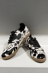Championes de cuero vacuno con acabado brillante tipo charol, color azul marino, con cordones al tono y suela de goma color caramelo.