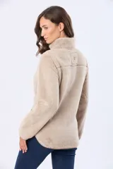 Campera de sherpa color beige con cuello alto y cierre frontal. Presenta un bolsillo frontal en el pecho de gamuza color arena con cierre y etiqueta decorativa, además de detalles en gamuza en los bordes.