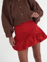 Falda corta estilo balloon de color rojo intenso, con cintura marcada y volumen fruncido en el ruedo.
