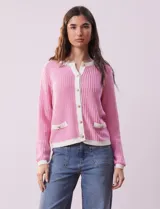 Cardigan de tejido tweed celeste y blanco, con escote redondo, cierre frontal con botones metálicos dorados y bolsillos simulados en el frente.