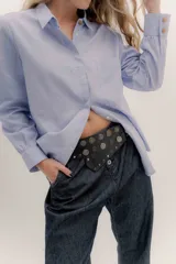 Faja de cuero color tostado con diseño de tachas metálicas circulares grabadas y cierre frontal con hebilla.