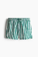 Short de baño con estampado de rayas verticales en color verde y blanco. Presenta cintura elástica con cordón de ajuste, bolsillos laterales y un bolsillo trasero con cierre autoadherente. Incluye suspensor interior de malla y aberturas laterales en el ruedo.