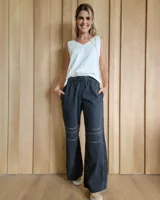 Pantalón de algodón color arena, de corte recto y holgado, con cintura elástica y detalle de costuras horizontales decorativas en la parte inferior de las piernas.