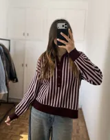 Sweater de punto a rayas verticales en tonos bordó y rosado, con cuello polo, cierre frontal con botones y puños y dobladillo en rib.