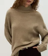 Suéter de punto de corte oversize y largo alargado, con cuello alto, mangas largas y aberturas laterales sutiles. Presenta puños y ruedo con acabado acanalado.