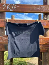 Remera blanca de algodón con estampado azul de la palabra "Tranca" en el frente.