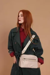 Bandolera de diseño moderno y funcional, confeccionada en nylon color marrón claro. Cuenta con múltiples compartimentos con cierre metálico, herrajes plateados y una correa ancha ajustable con detalle de marca.