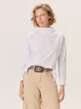 Remera blanca de manga larga con cuello alto, corte holgado y costuras verticales decorativas en el frente.