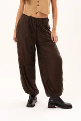 Pantalón tipo babucha de encaje color chocolate, con forro interior, cintura regulable y elásticos en los tobillos que generan una silueta abuchonada.